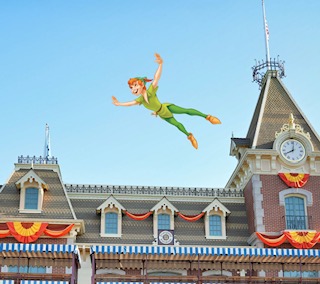 Peter Pan flying in front of a castle with clock tower at Disneyland